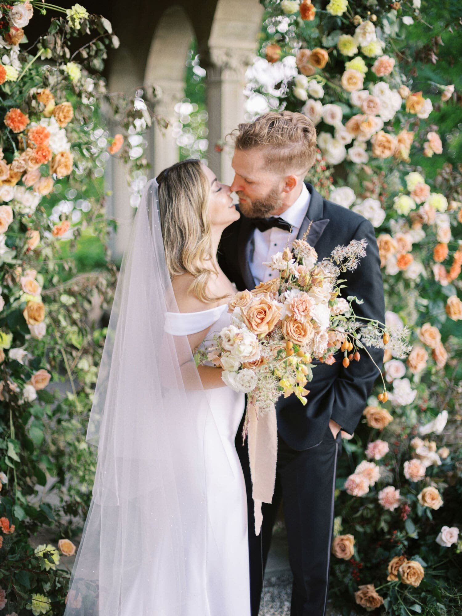 Wedding couple in front of the ceremony arch during their Villa Le Fontanelle wedding in Tuscany