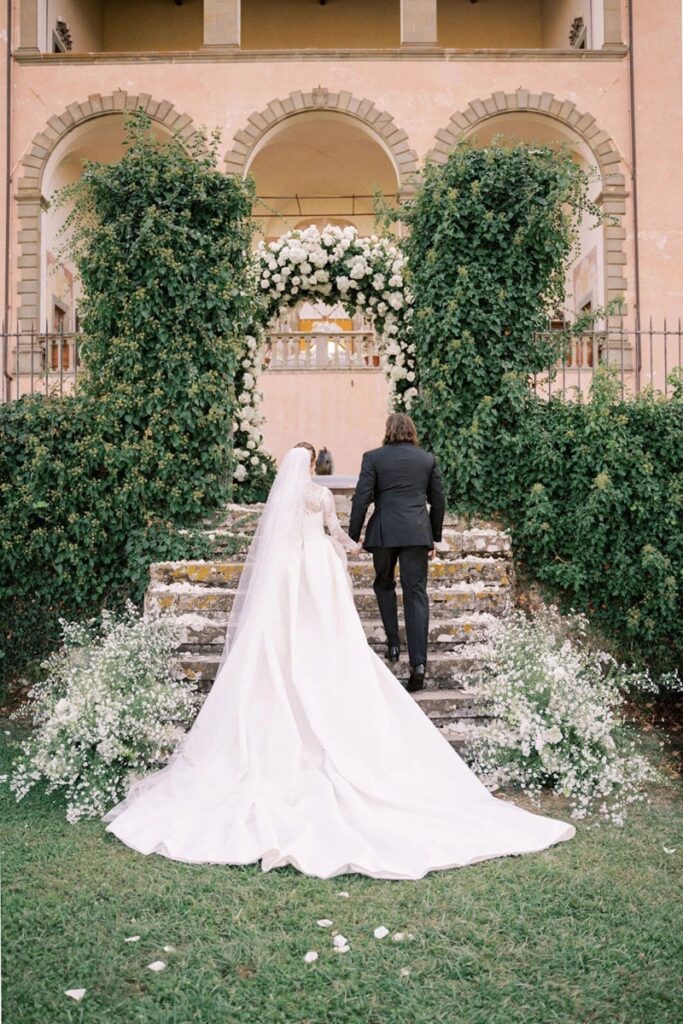 Wedding couple walking up the stairs through an arch at their Mangiacane Wedding in Tuscany